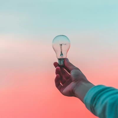 A lightbulb taken by a hand at sunset